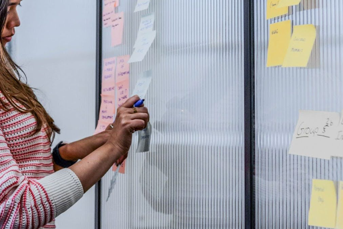 JBi employee attaching a post it note to the wall during a workshop